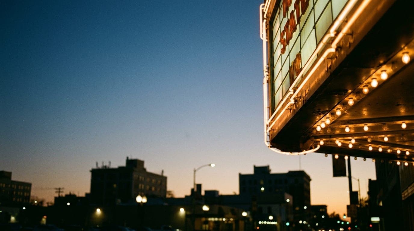 A 35mm macro shot captures the intricate, glowing marquee lights of the historic State Theatre at dusk, offset right again...