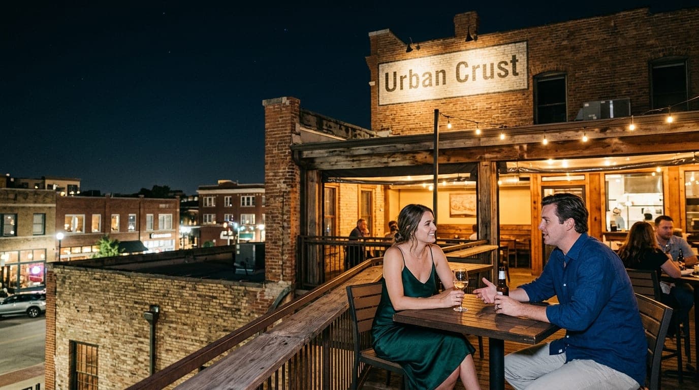 A couple sits on the rooftop deck of Urban Crust in Downtown Plano. Brick architecture frames the night sky. The woman wea...