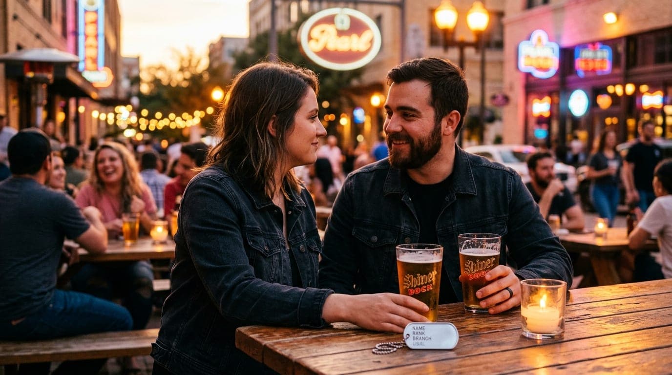 A couple in dark denim sits at a sun-drenched Pearl patio table. A polished silver military dog tag rests beside a half-em...