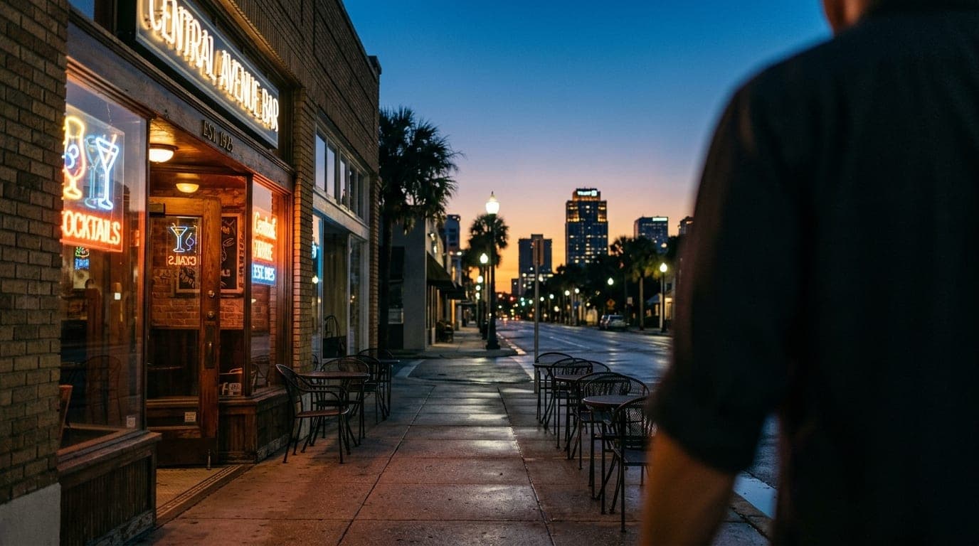 The neon-lit facade of a Central Avenue cocktail bar glows softly during blue hour. Empty bistro chairs line the sidewalk,...