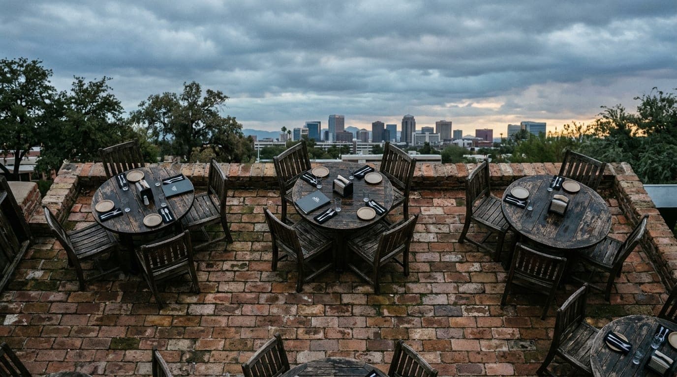 An overhead, 50mm flat-lay view of the weathered, dark wooden outdoor tables at Casey Moore’s Oyster House during an overc...