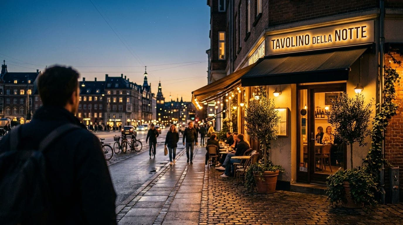An eye-level 35mm shot of the illuminated Tavolino Della Notte storefront at dusk. The warm glow spills onto the sidewalk,...