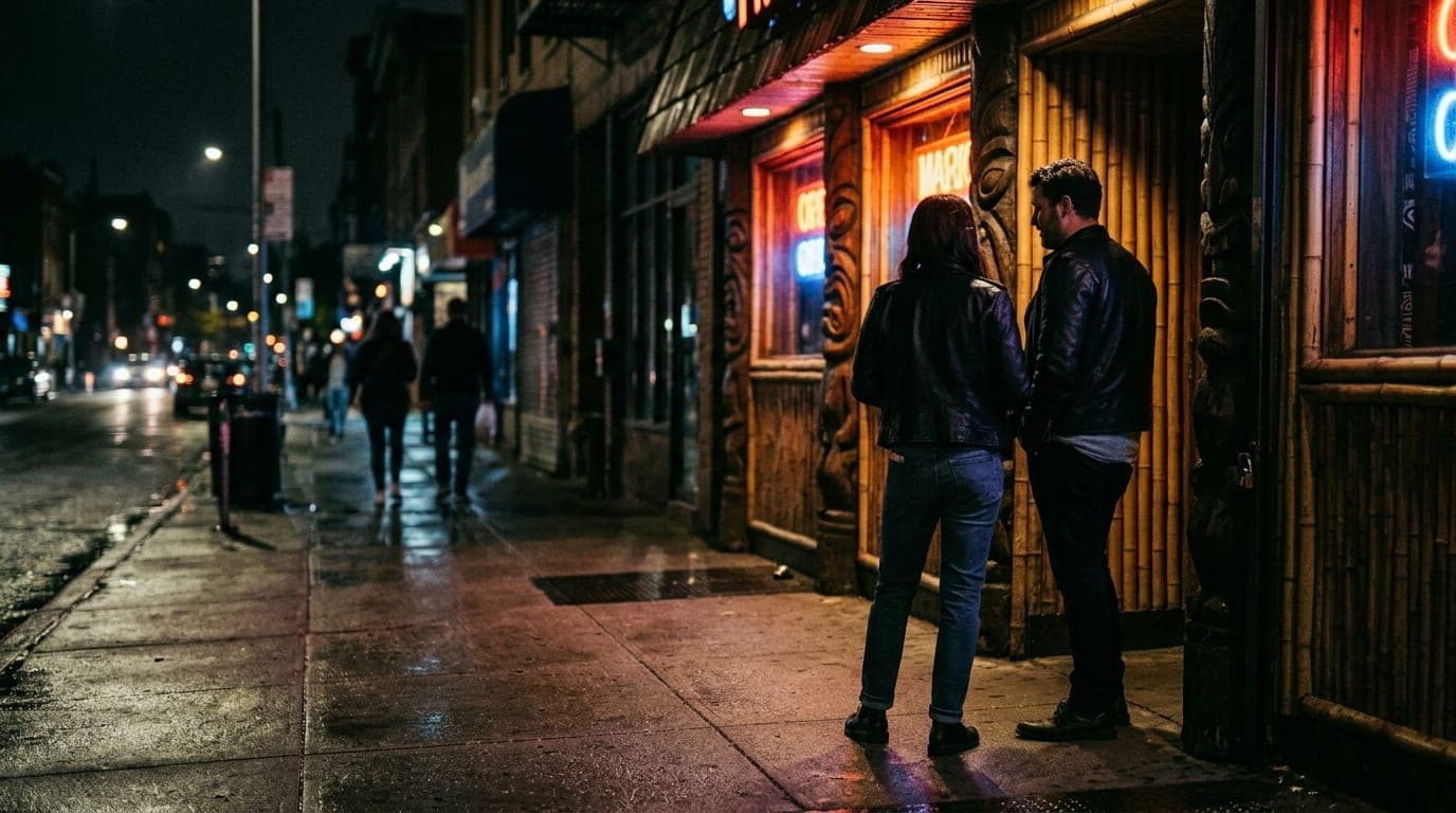 A low-angle 35mm shot at midnight outside The Inferno Room. A leather-clad couple stands on the rain-slicked Fletcher Plac...