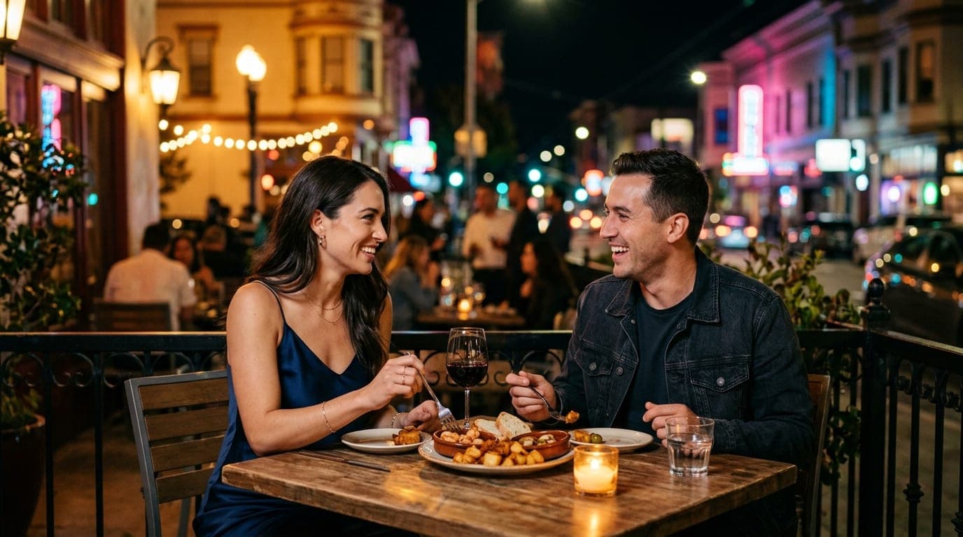 A couple shares a plate of tapas on the Luna Red patio at night. The woman wears a silk slip dress; the glowing Mission li...