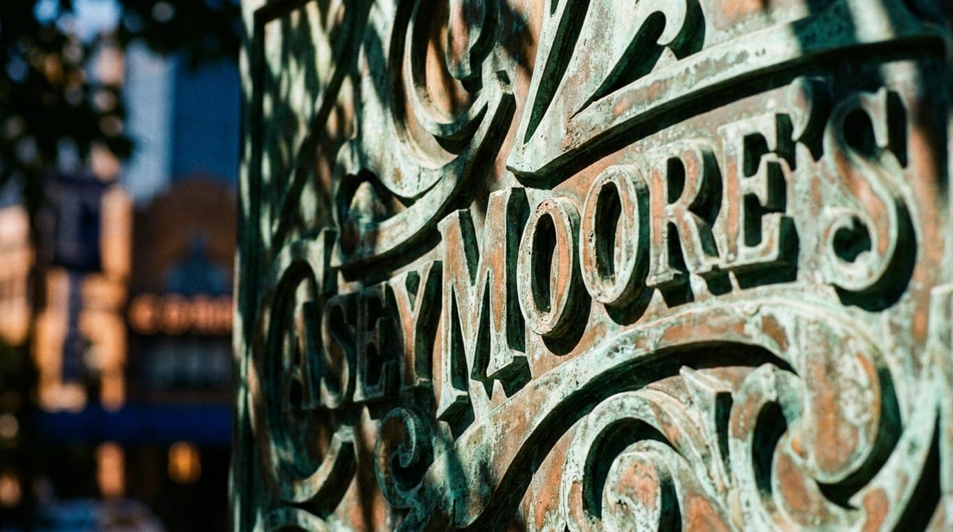 A 100mm macro shot captures the intricate, oxidized copper details of the historic Casey Moore’s signage, illuminated by c...
